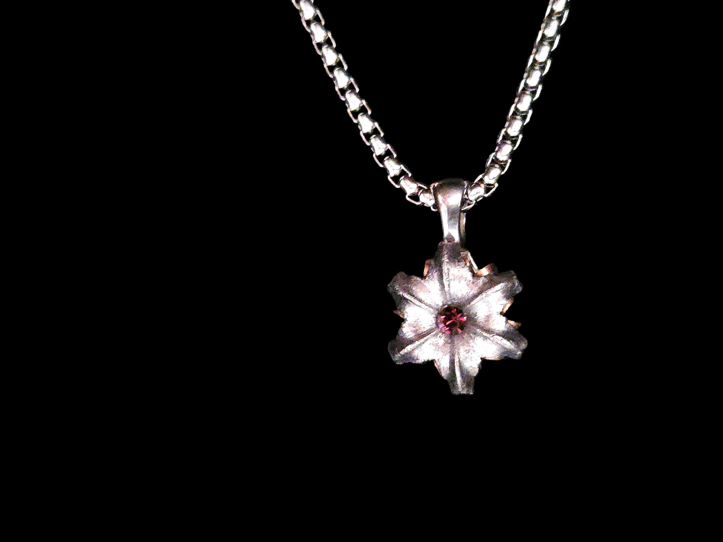 Silver flower pendant necklace on a black background