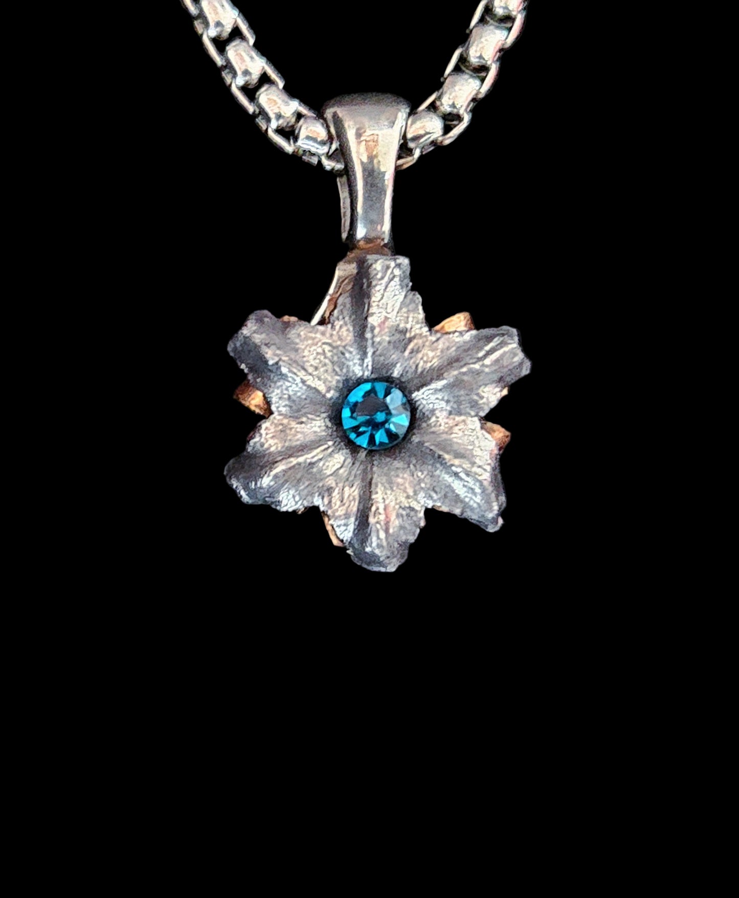 Floral pendant with blue gemstone on a black background
