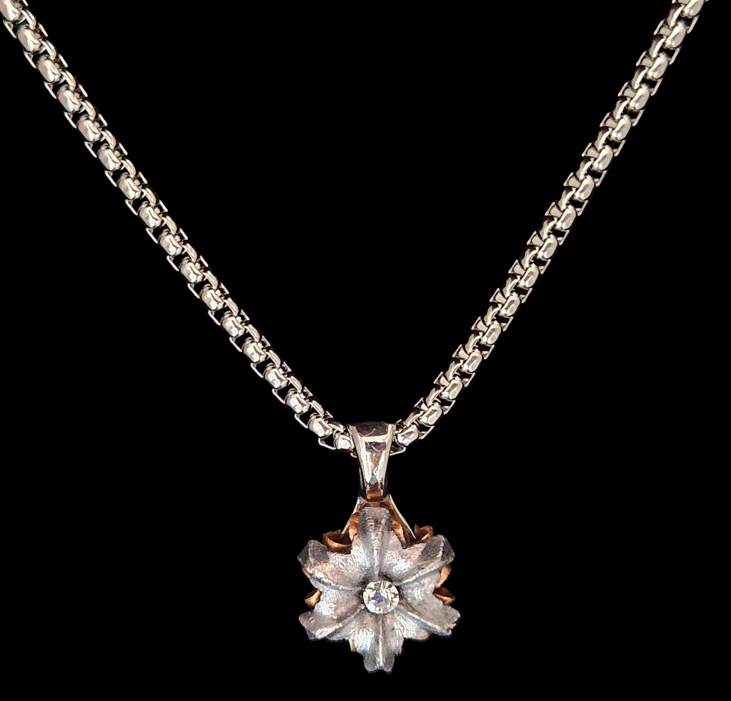 Silver necklace with a star-shaped pendant on a black background