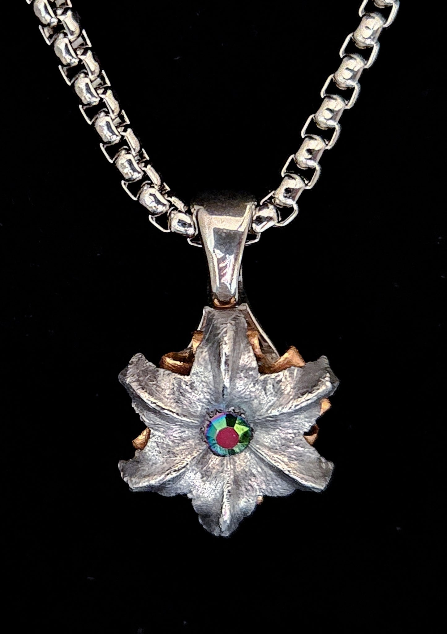 Silver flower-shaped pendant with a colorful gemstone on a black background