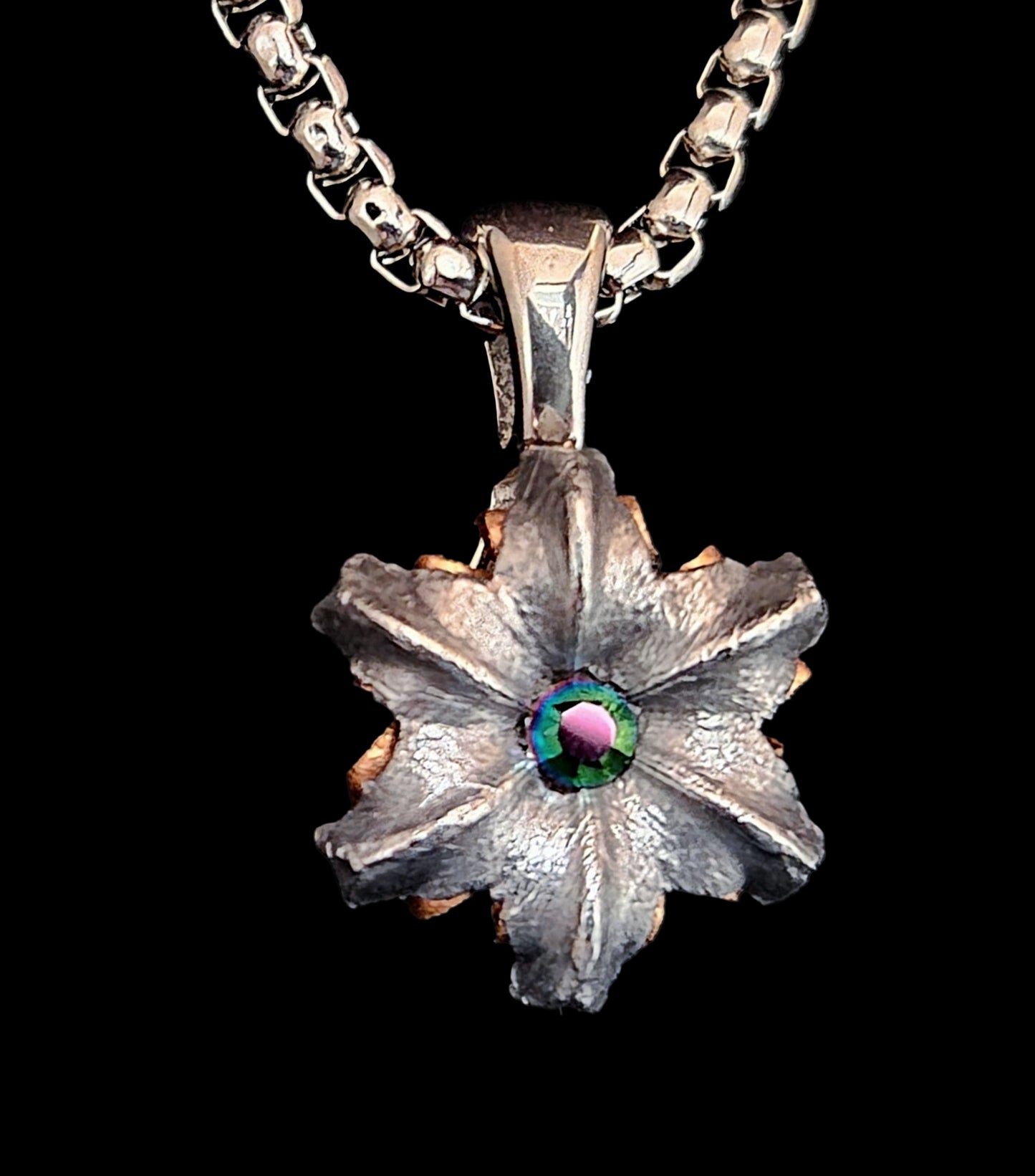Silver flower-shaped pendant with a central gemstone on a black background