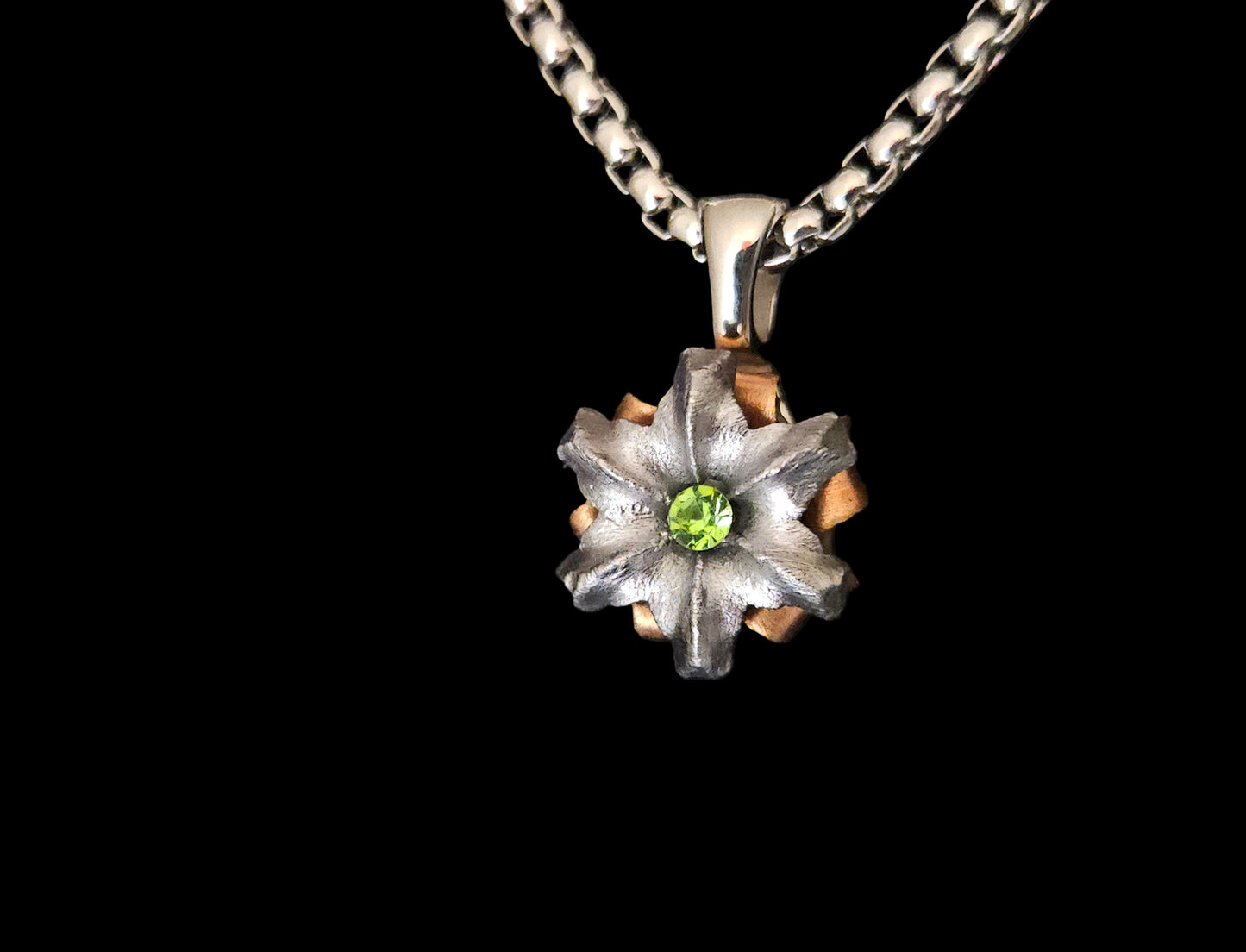 Floral pendant necklace with a green gemstone on a black background