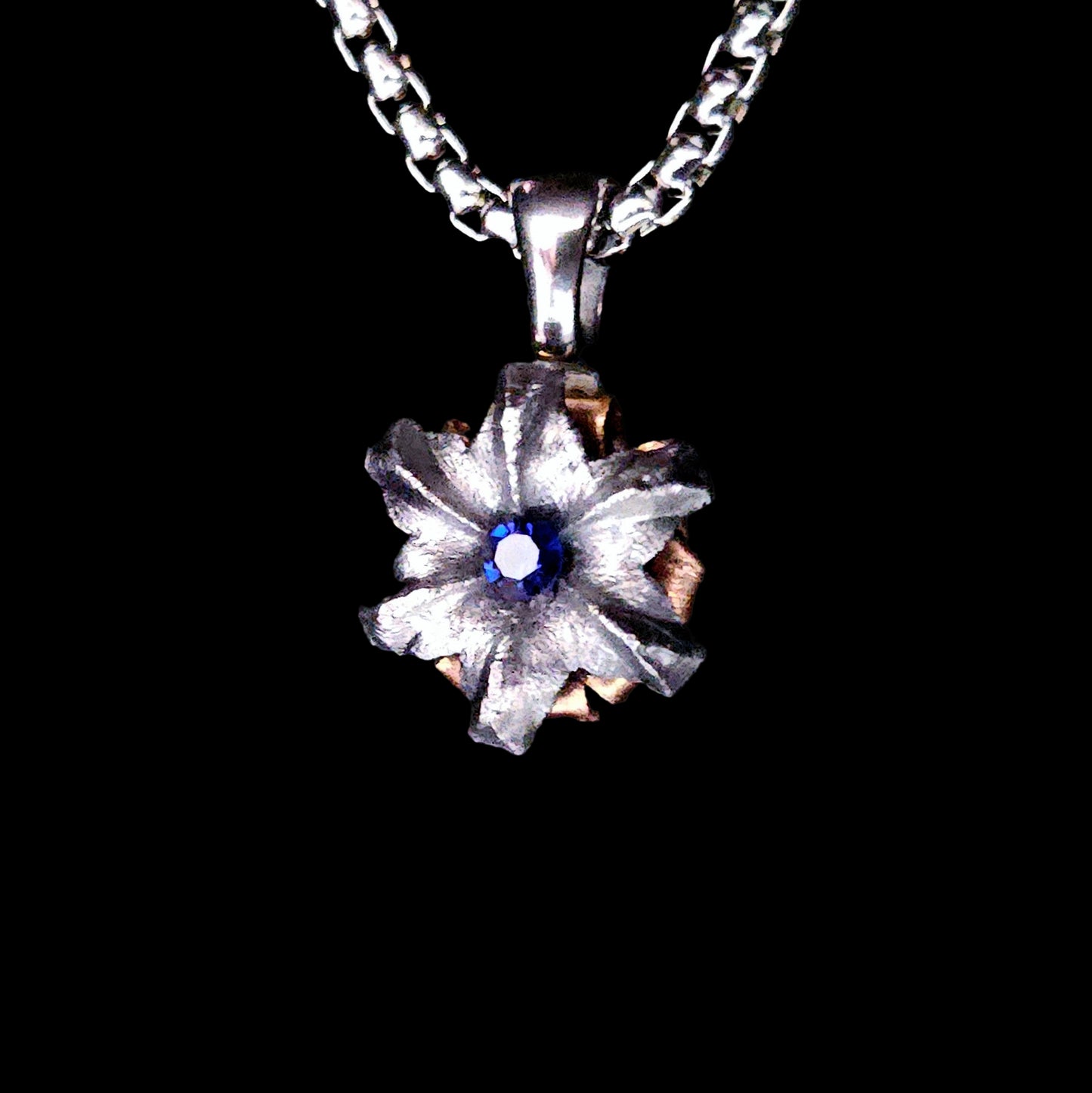 Floral pendant necklace with a blue gemstone on a black background