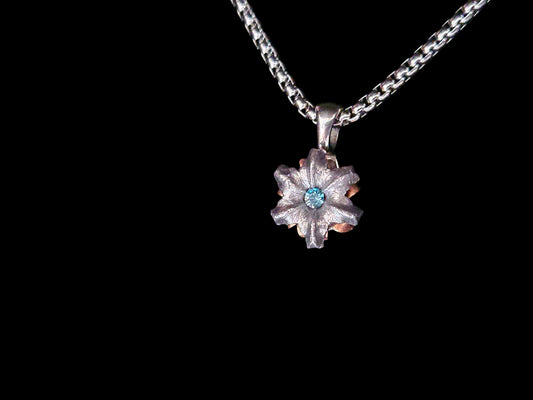 Silver necklace with a flower-shaped pendant on a black background