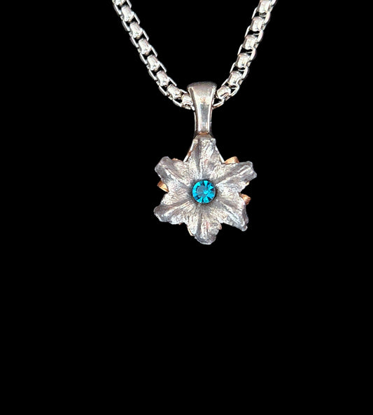 Silver pendant with a blue gemstone on a black background