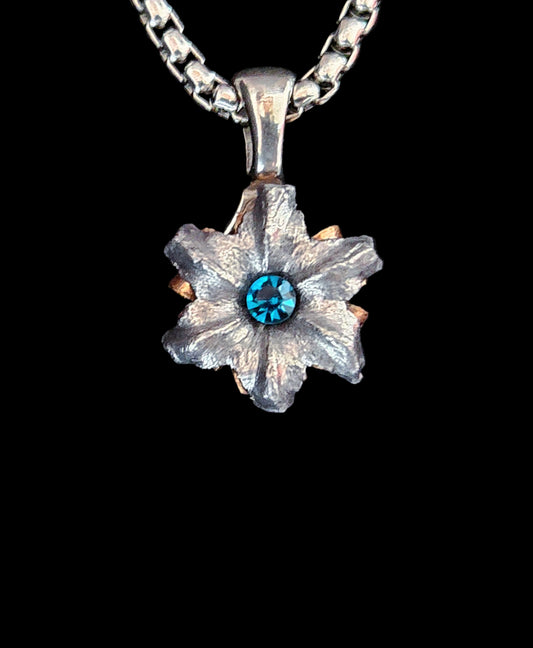 Floral pendant with blue gemstone on a black background