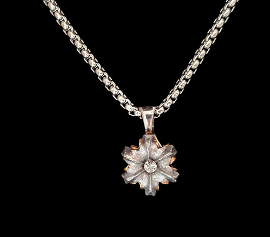 Silver necklace with a flower shaped pendant on a black background