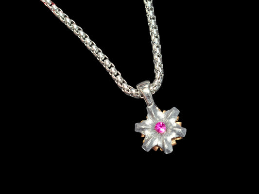 Silver necklace with a deep pink floral pendant on a black background. 