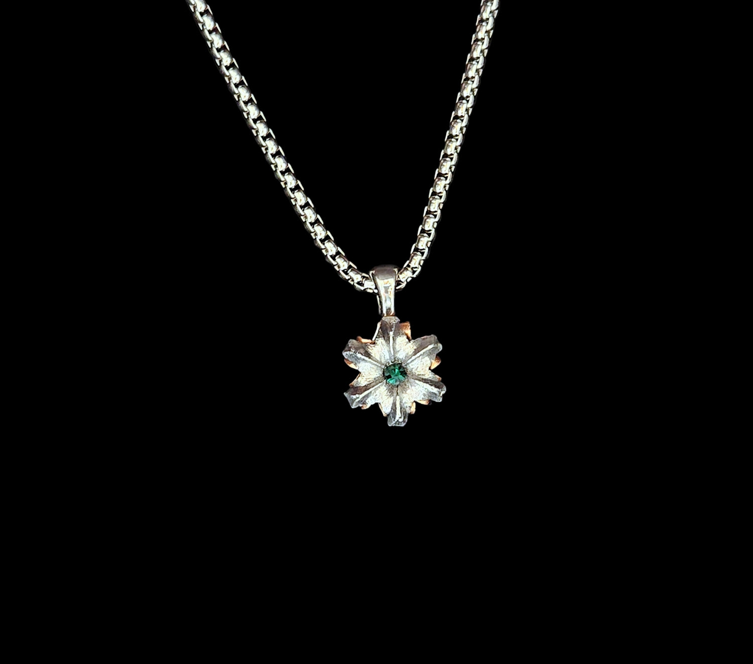 Silver necklace with a flower-shaped pendant on a black background