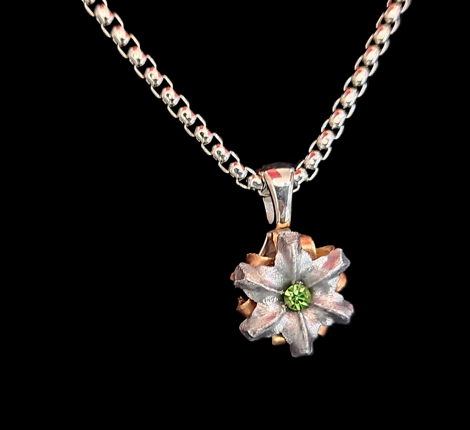Floral pendant necklace with a green gemstone on a black background