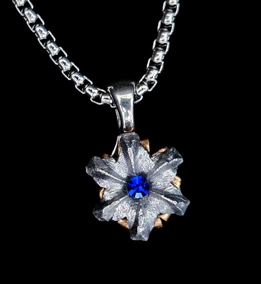 Silver necklace with a floral pendant featuring a blue gemstone on a black background