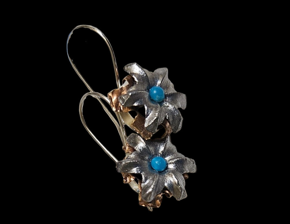 Floral earrings with blue turquoise centers on a black background