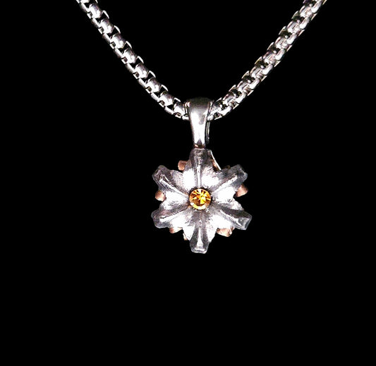 Silver flower-shaped pendant with a yellow center on a black background