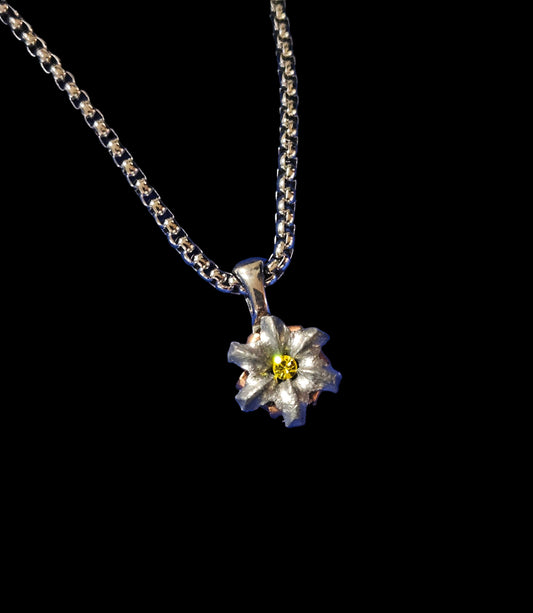 Silver necklace with a flower pendant on a blue textured background