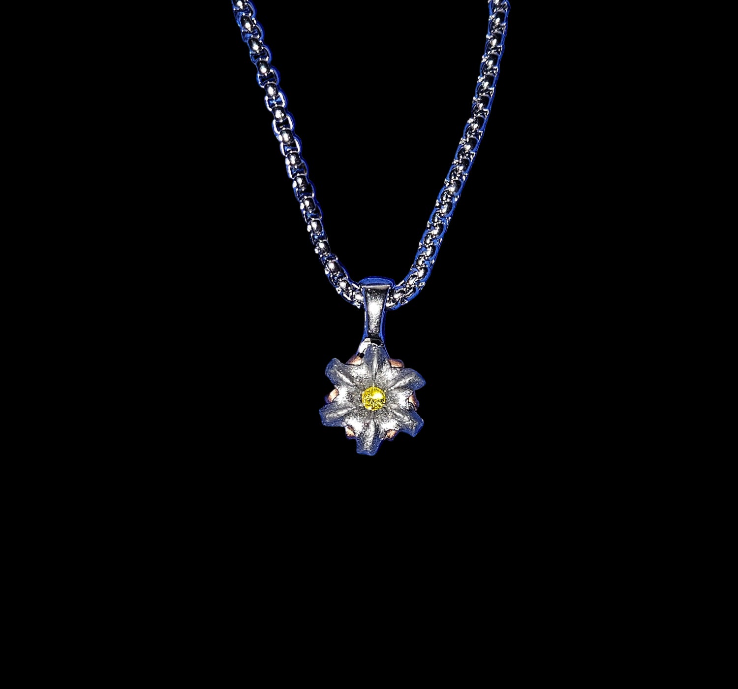 Silver necklace with a flower pendant on a blue textured background