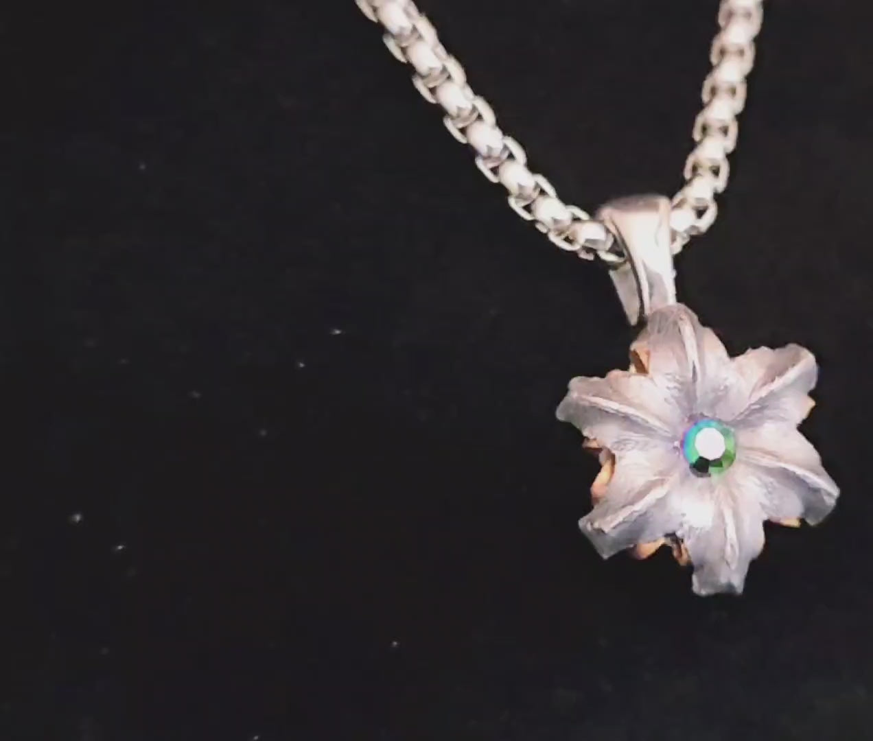 Video of a multicolored crystal set in the center of a floral pendant. 